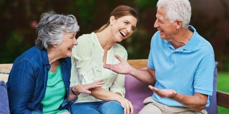 Daughter Talking with Elderly Parents on Bench at Memory Care Facility